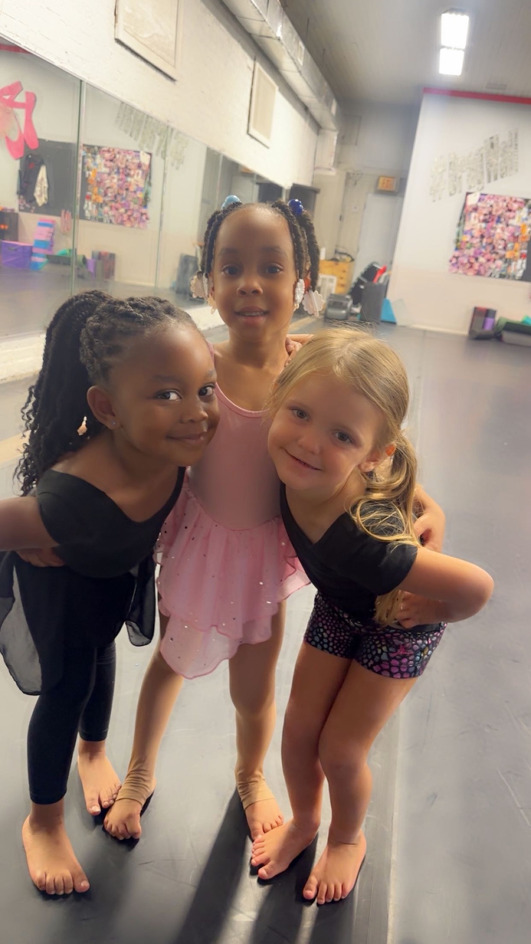 Three young Premiere dancers smiling together in the studio.